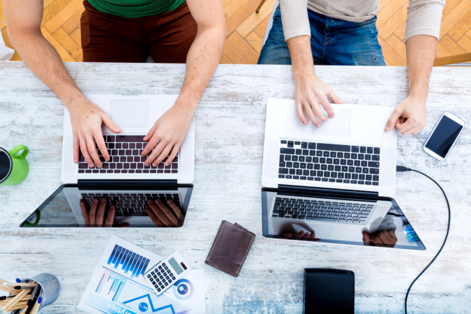 Two work colleagues on laptops from a birds-eye view