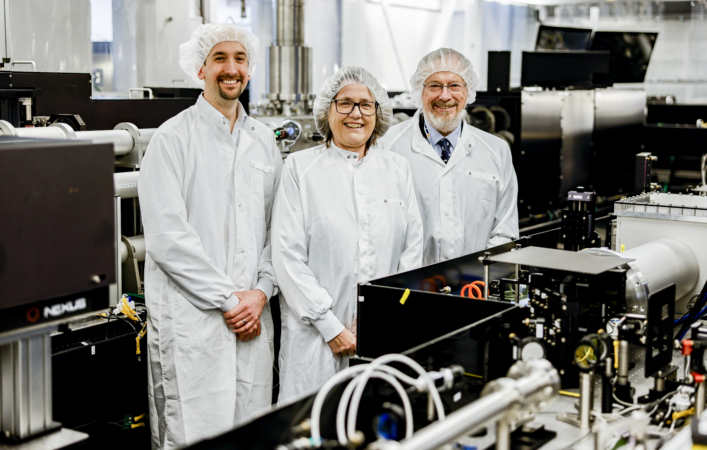 Three people in protective workwear in a lab