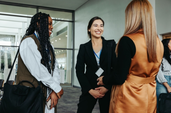 Three professional women in business clothing chatting in an office