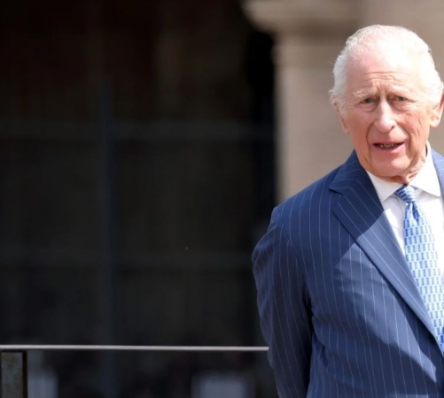 HRH King Charles looking directly at the camera stood against a blurred background