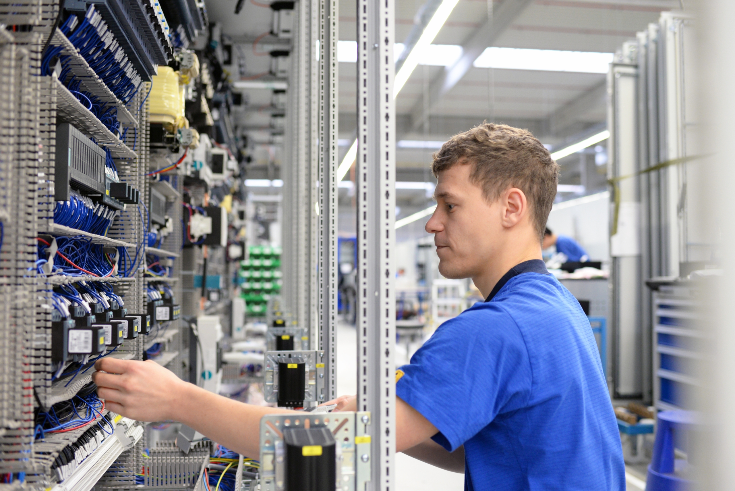 young operator assembles machine in a modern high tech factory - production of switch cabinets for industrial plant